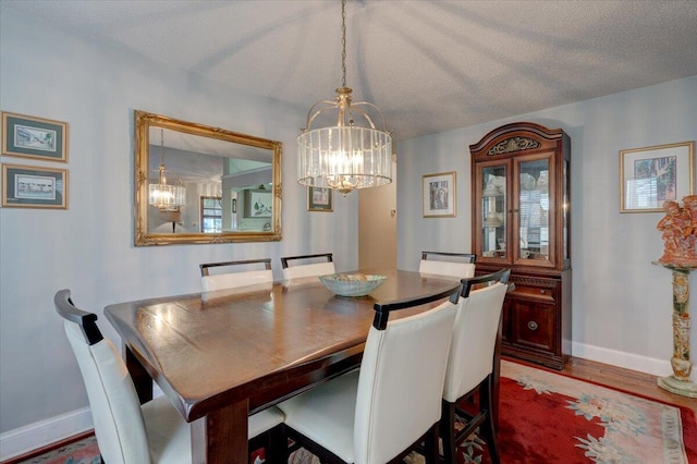 dining area featuring an inviting chandelier, hardwood / wood-style floors, and a textured ceiling