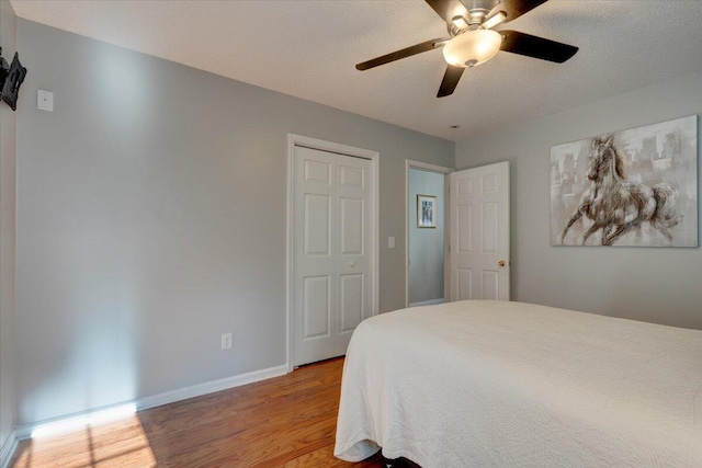 bedroom with ceiling fan, a textured ceiling, light wood-type flooring, and a closet