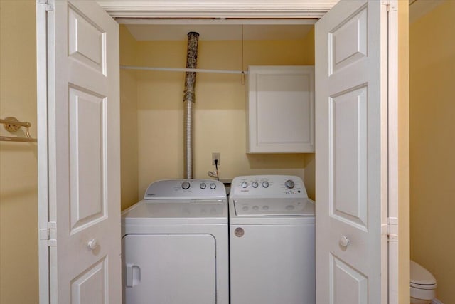 clothes washing area with washing machine and dryer and cabinets