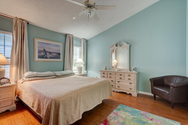 bedroom featuring hardwood / wood-style flooring, ceiling fan, lofted ceiling, and a textured ceiling