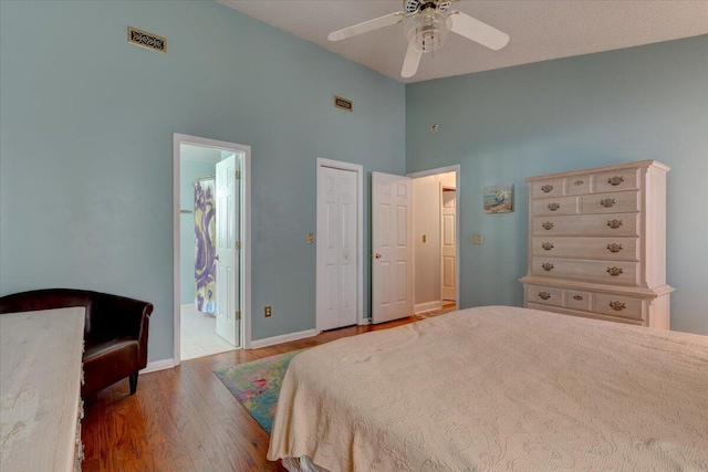 bedroom featuring ceiling fan, connected bathroom, high vaulted ceiling, and light hardwood / wood-style flooring