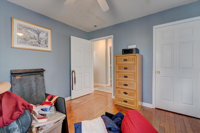 bedroom with ceiling fan, a textured ceiling, and light wood-type flooring