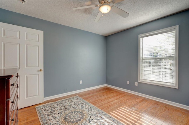 spare room featuring ceiling fan, light hardwood / wood-style flooring, and a textured ceiling