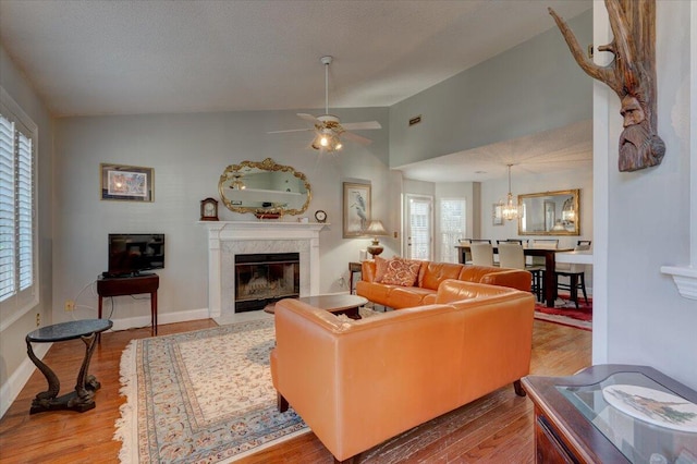 living room featuring hardwood / wood-style flooring, a high end fireplace, vaulted ceiling, and a textured ceiling