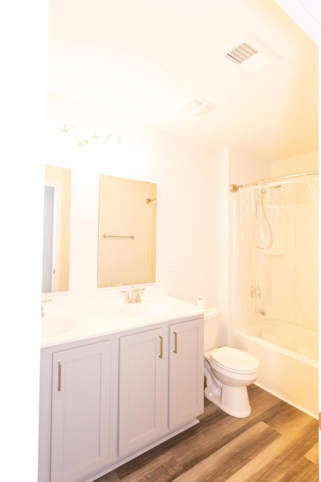 full bathroom featuring hardwood / wood-style flooring, shower / bath combo, vanity, and toilet