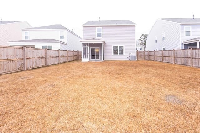 rear view of house featuring a yard, central AC, and a sunroom