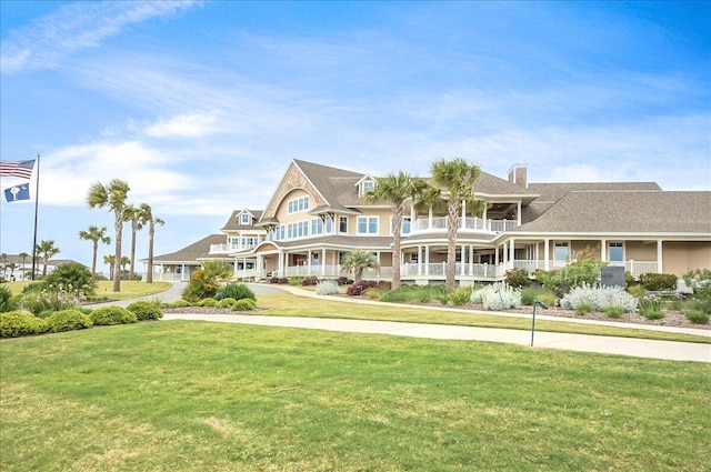 view of front of home featuring a chimney, a front yard, and a balcony