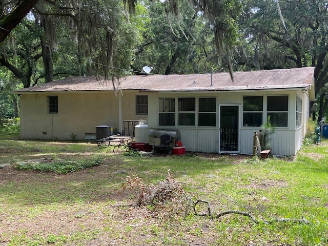 back of property featuring central AC and a lawn