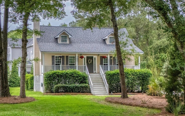 cape cod home with stairs, a front yard, covered porch, a chimney, and a shingled roof