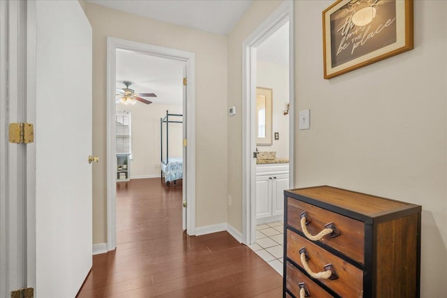 corridor with dark wood-style flooring and baseboards
