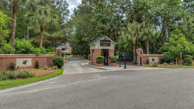 view of asphalt street with a gate and view of scattered trees