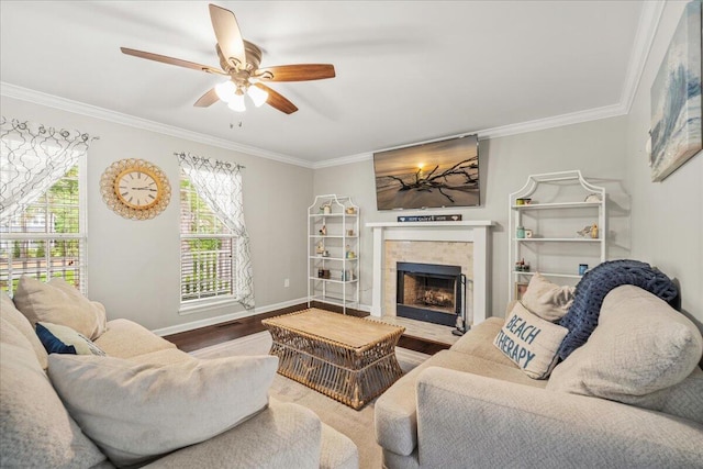 living room with ornamental molding, a tile fireplace, ceiling fan, wood finished floors, and baseboards