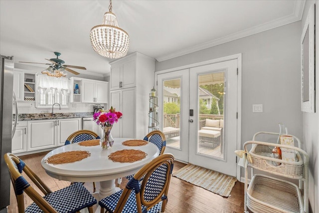dining room with french doors, a ceiling fan, crown molding, a chandelier, and wood finished floors