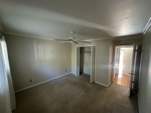 unfurnished bedroom with carpet, a closet, ceiling fan, and ornamental molding