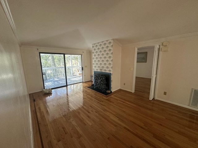 unfurnished living room featuring wood-type flooring and ornamental molding