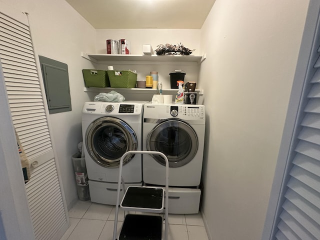 clothes washing area featuring light tile patterned floors, electric panel, and washing machine and clothes dryer