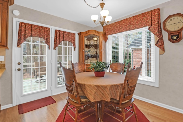 dining area featuring a chandelier, wood-type flooring, and a healthy amount of sunlight