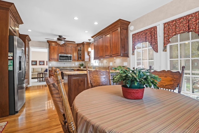 dining space featuring ceiling fan, light wood-type flooring, and sink