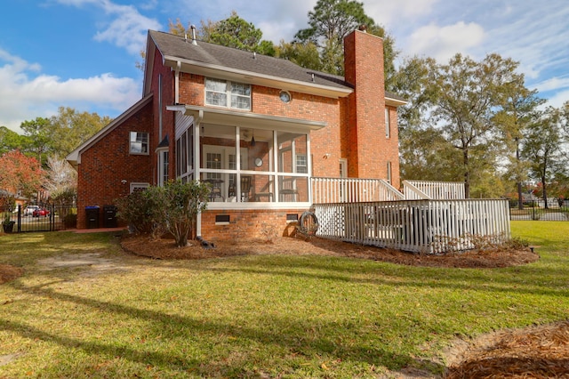 back of house featuring a deck, a lawn, and a sunroom