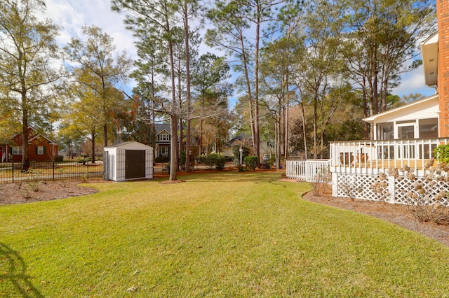 view of yard with a sunroom, a storage shed, and a wooden deck