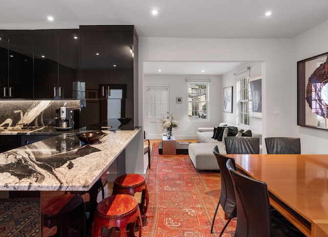 kitchen with light stone countertops, a breakfast bar area, backsplash, and sink