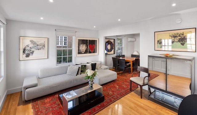 living room featuring wood-type flooring and an AC wall unit