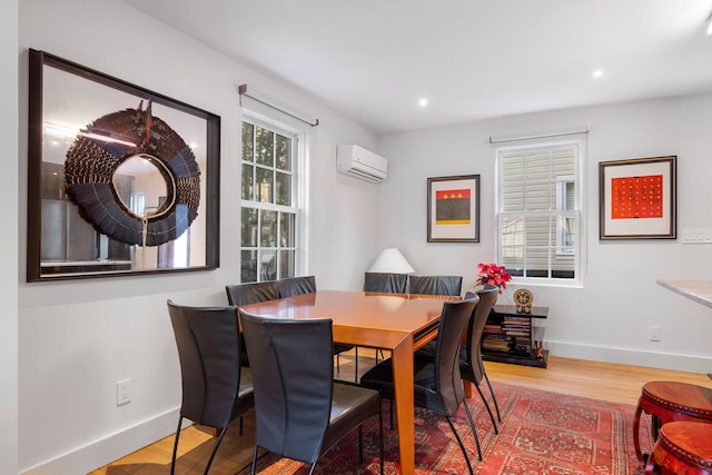 dining area with a wall mounted air conditioner and light hardwood / wood-style flooring