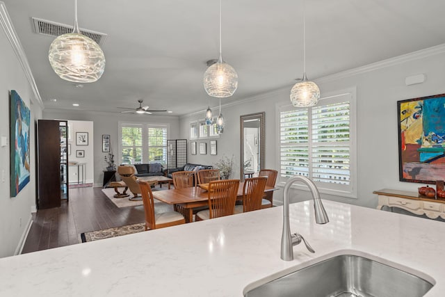 kitchen with hardwood / wood-style flooring, crown molding, visible vents, and a sink