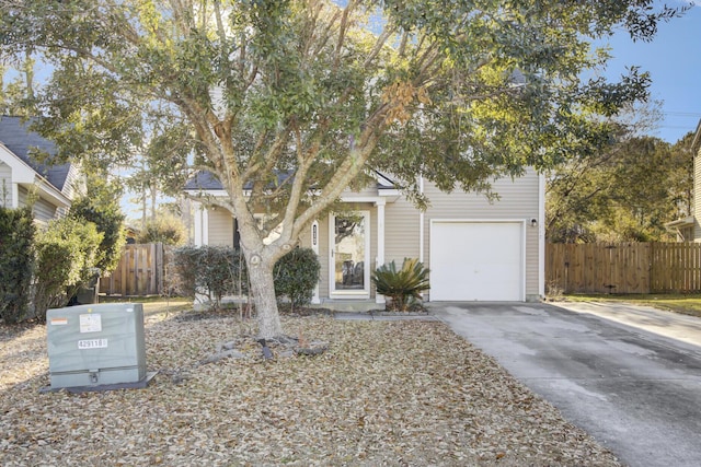 view of property hidden behind natural elements with an attached garage, fence, and concrete driveway