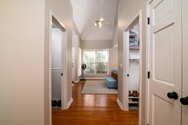 corridor featuring lofted ceiling, dark wood-style floors, and baseboards