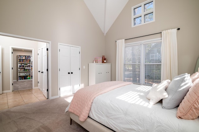 carpeted bedroom with baseboards, high vaulted ceiling, a closet, and tile patterned floors