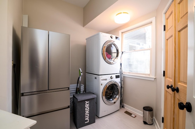 laundry area featuring stacked washer / drying machine, laundry area, and baseboards