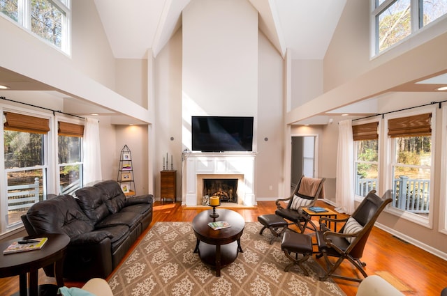 living area with a high ceiling, wood finished floors, a high end fireplace, and baseboards