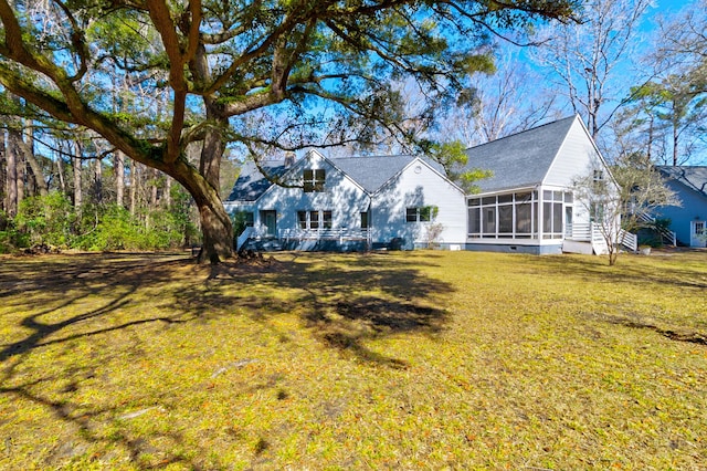 rear view of property with a lawn and a sunroom