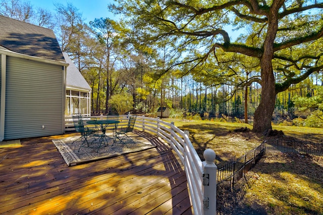 wooden deck with outdoor dining space, a sunroom, and fence