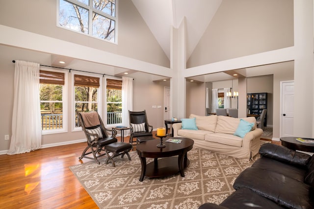 living room featuring recessed lighting, an inviting chandelier, wood finished floors, high vaulted ceiling, and baseboards