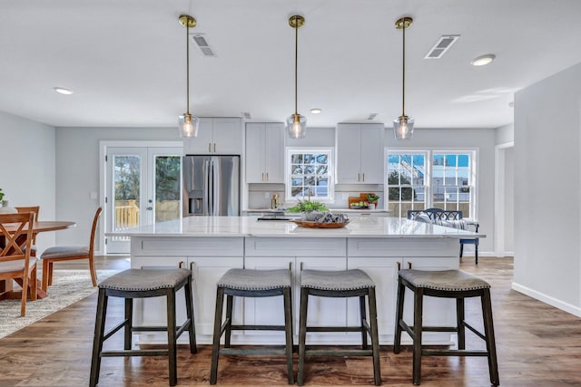 kitchen featuring hanging light fixtures, a breakfast bar area, stainless steel fridge, and a spacious island