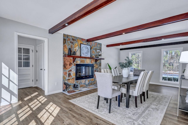 dining space featuring hardwood / wood-style flooring, a fireplace, and beam ceiling