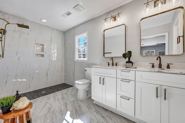 bathroom featuring a tile shower, vanity, and toilet