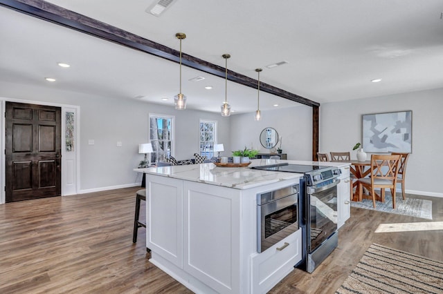 kitchen featuring decorative light fixtures, white cabinetry, a center island, electric range, and light stone counters