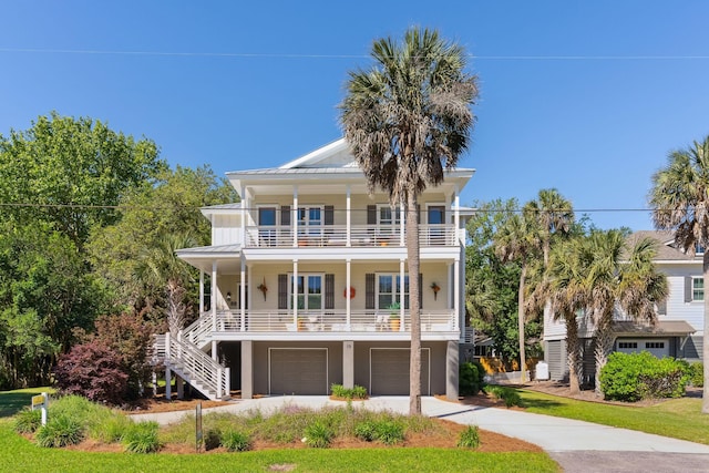 raised beach house featuring a balcony, covered porch, and a garage