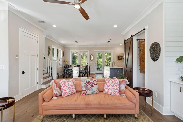 dining area with an inviting chandelier, crown molding, sink, a barn door, and light wood-type flooring