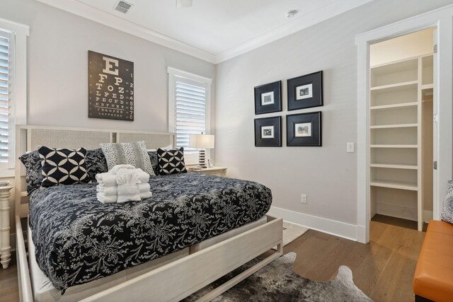 bedroom with crown molding, a spacious closet, and hardwood / wood-style flooring