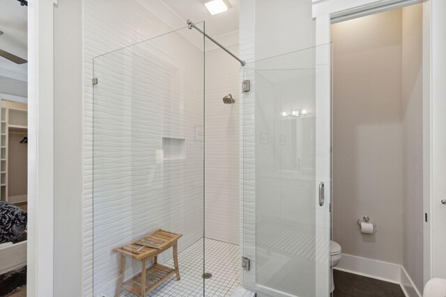 bathroom featuring toilet, an enclosed shower, and ceiling fan