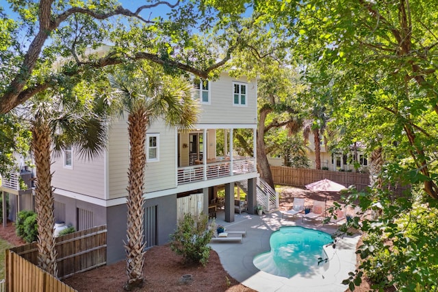 back of property featuring a fenced in pool and a patio area