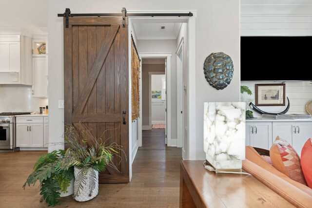 interior space featuring a barn door, ornamental molding, and hardwood / wood-style floors