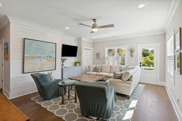 living room featuring wood walls, dark wood-type flooring, ceiling fan, and ornamental molding