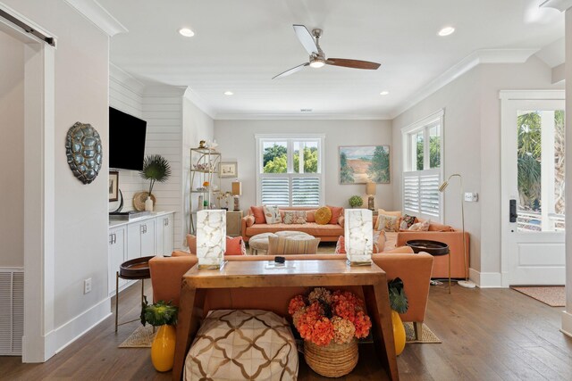 living room with ornamental molding, wood-type flooring, ceiling fan, and a barn door