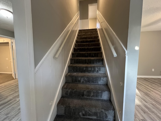 stairway with hardwood / wood-style flooring and a textured ceiling