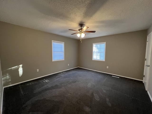 empty room featuring dark colored carpet, a textured ceiling, and ceiling fan